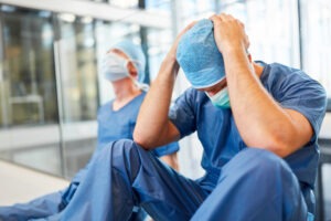 Frustrated healthcare professionals sit on the floor after medical malpractice in California. Contact a California medical malpractice lawyer.