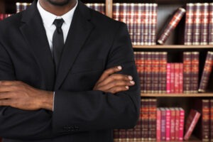 A Tesla mass action lawyer crosses his arms in front of a shelf of books.