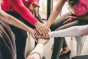 Group of women put hands together in solidarity.