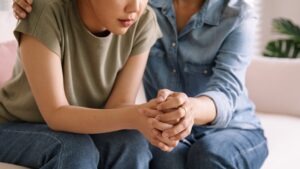 Two women holding hands in support after sexual abuse
