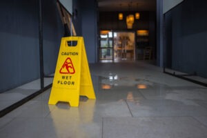 A wet floor sign is placed over a spill. Hire a Culver City slip-and-fall accident lawyer now.