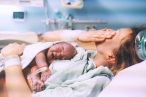 A mother holds a newborn baby before calling an Oakland birth injury lawyer.