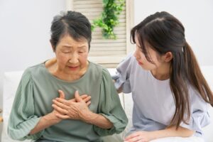 A woman sits on a sofa with her elder mother, who seems distressed. She tries to talk to her and wonders what the signs of elder sexual abuse are.